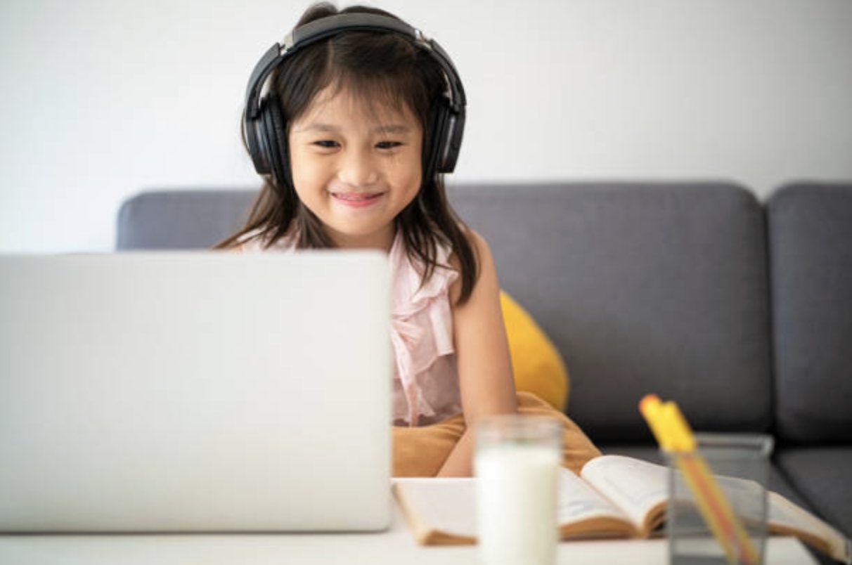 Student smiling while learning online with headphones